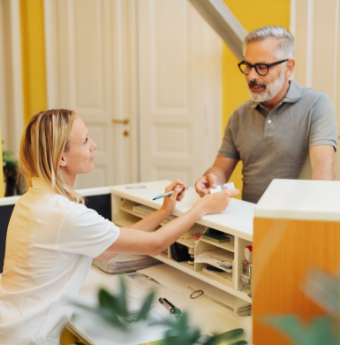 Female dental team member talking to male patient at front desk